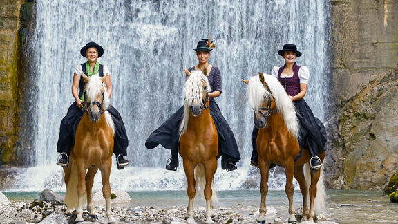 Frauen auf Pferde vor Wasserfall